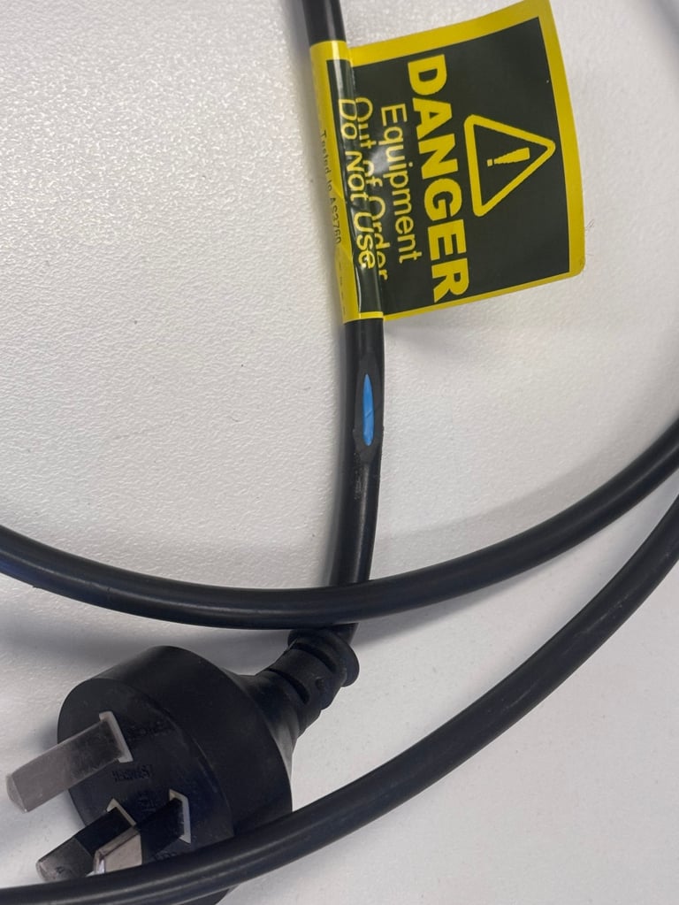 Black electrical power cord with UK plug and yellow danger caution label attached to cable