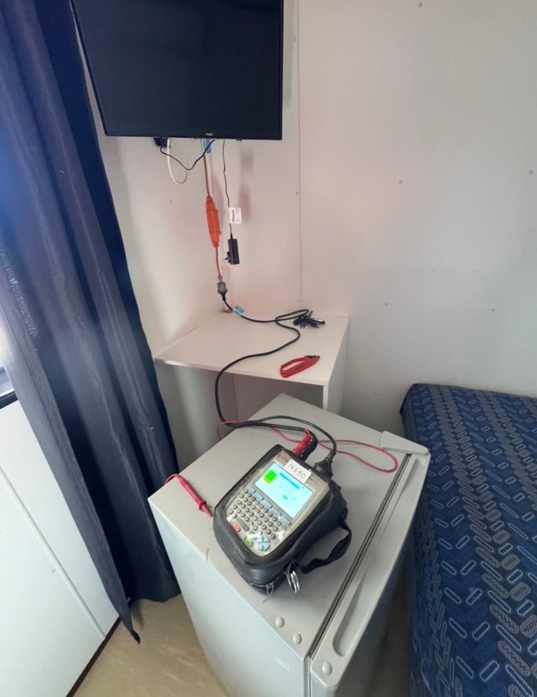 Diagnostic device with alligator clips connected to monitor mounted on wall above a bed in a small room