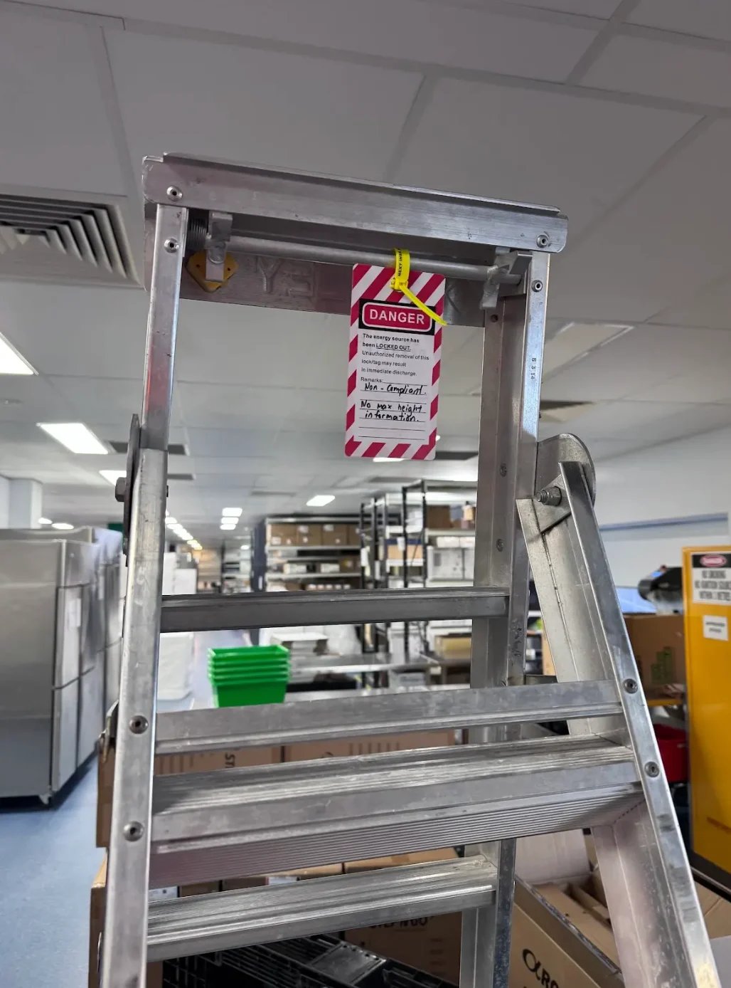 Metal ladder with red and white danger tag in commercial kitchen setting