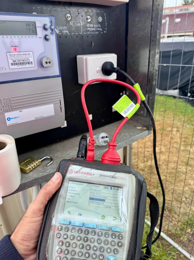 Technician holding a handheld diagnostic device connected to outdoor electrical equipment with red test cables