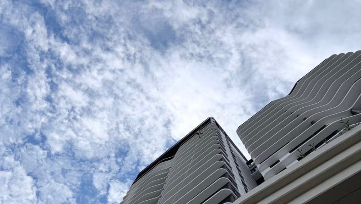 Low angle view of tall modern buildings against blue sky with white clouds