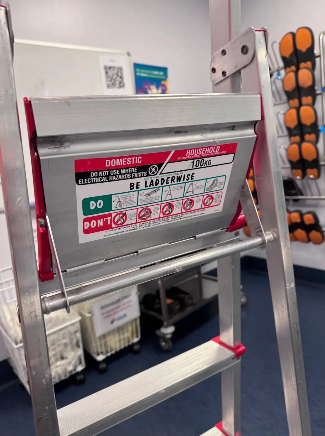 Domestic household ladder with red and white frame displaying safety instructions and DO/DONT warning labels