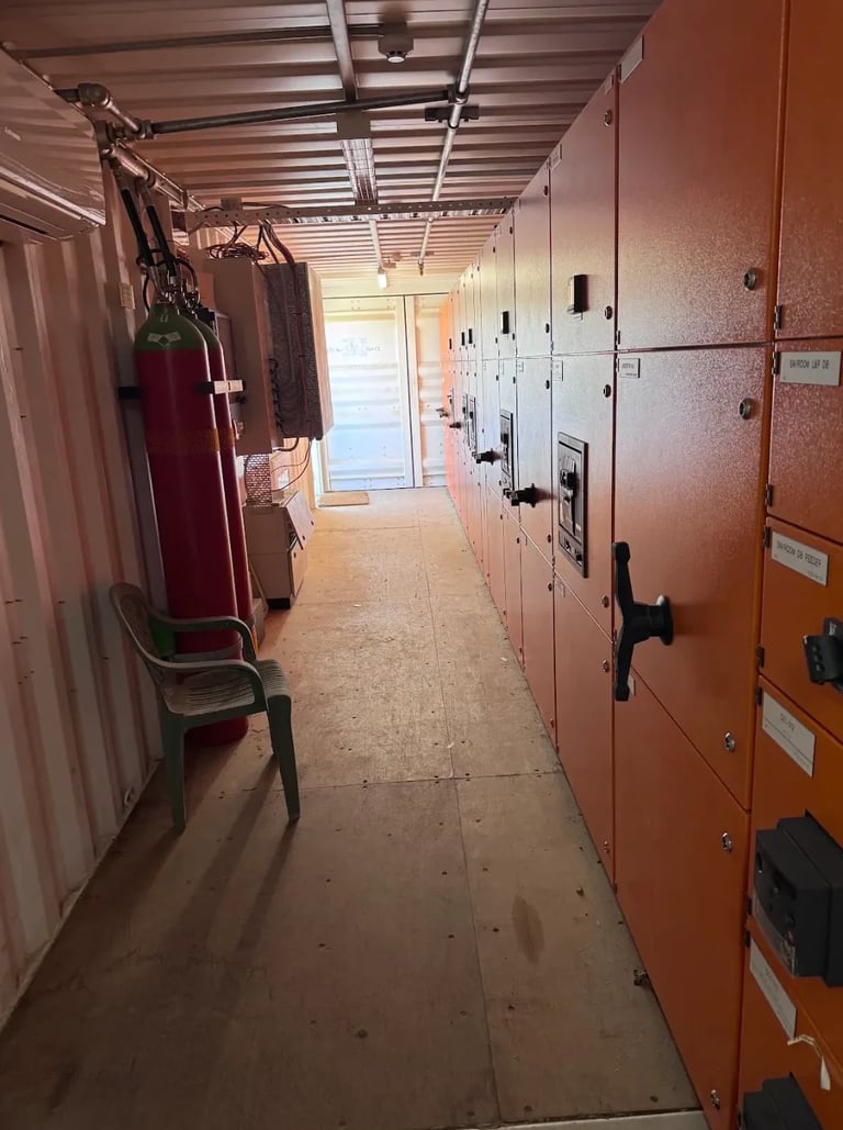 Interior of a storage facility hallway with orange metal locker units lining both sides and natural light entering from a door at the end