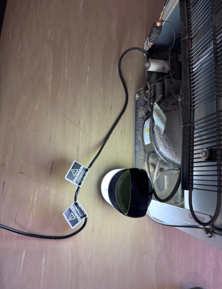 Overhead view of gaming headset with black and white ear cups connected to white console controller on wooden floor