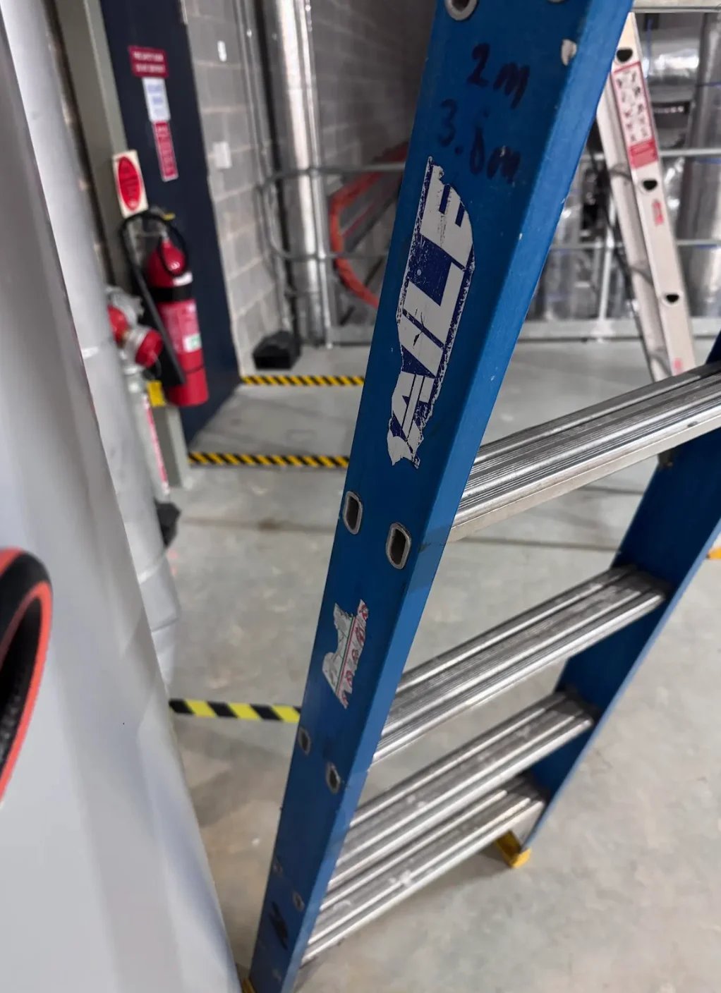 Close-up of blue extension ladder with metal rungs in a warehouse or garage setting