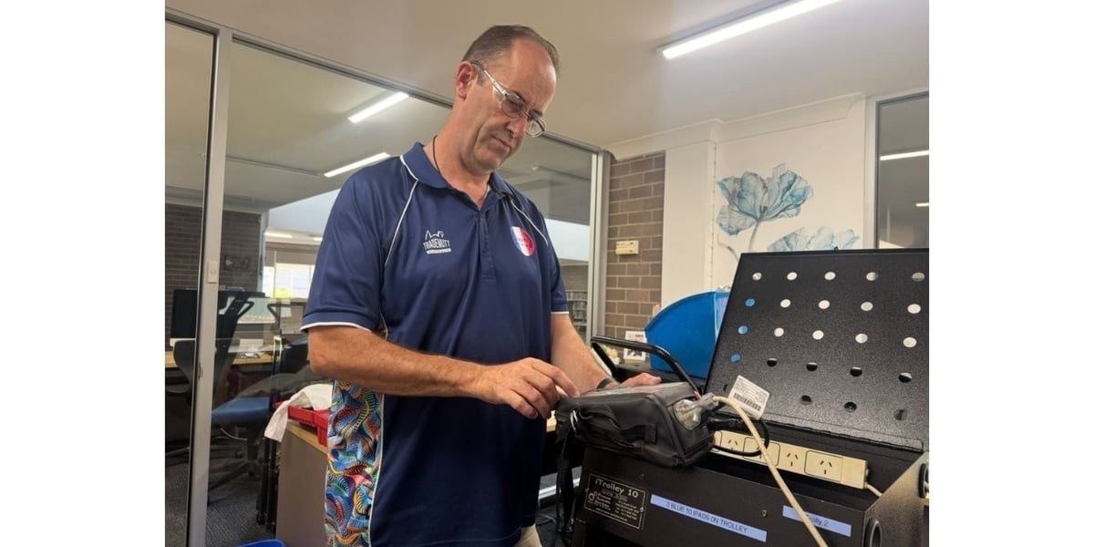 Man in blue polo shirt repairing or assembling electronic equipment in a workshop setting