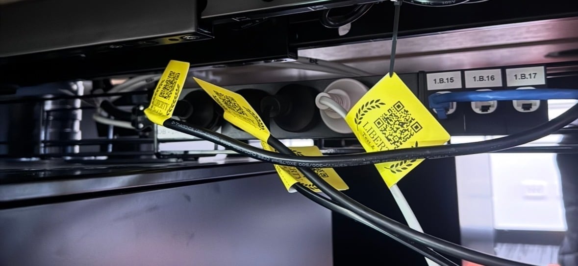 Yellow caution tags attached to electrical cords and cables on a black equipment shelf or rack