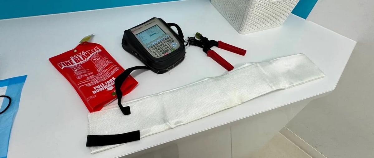 First aid kit contents displayed on white surface including red pouch, medical device, red handles, and gauze pads